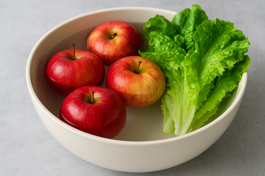 Fresh red apples and green lettuce soaking in a bowl of water for cleaning with chlorine dioxide.